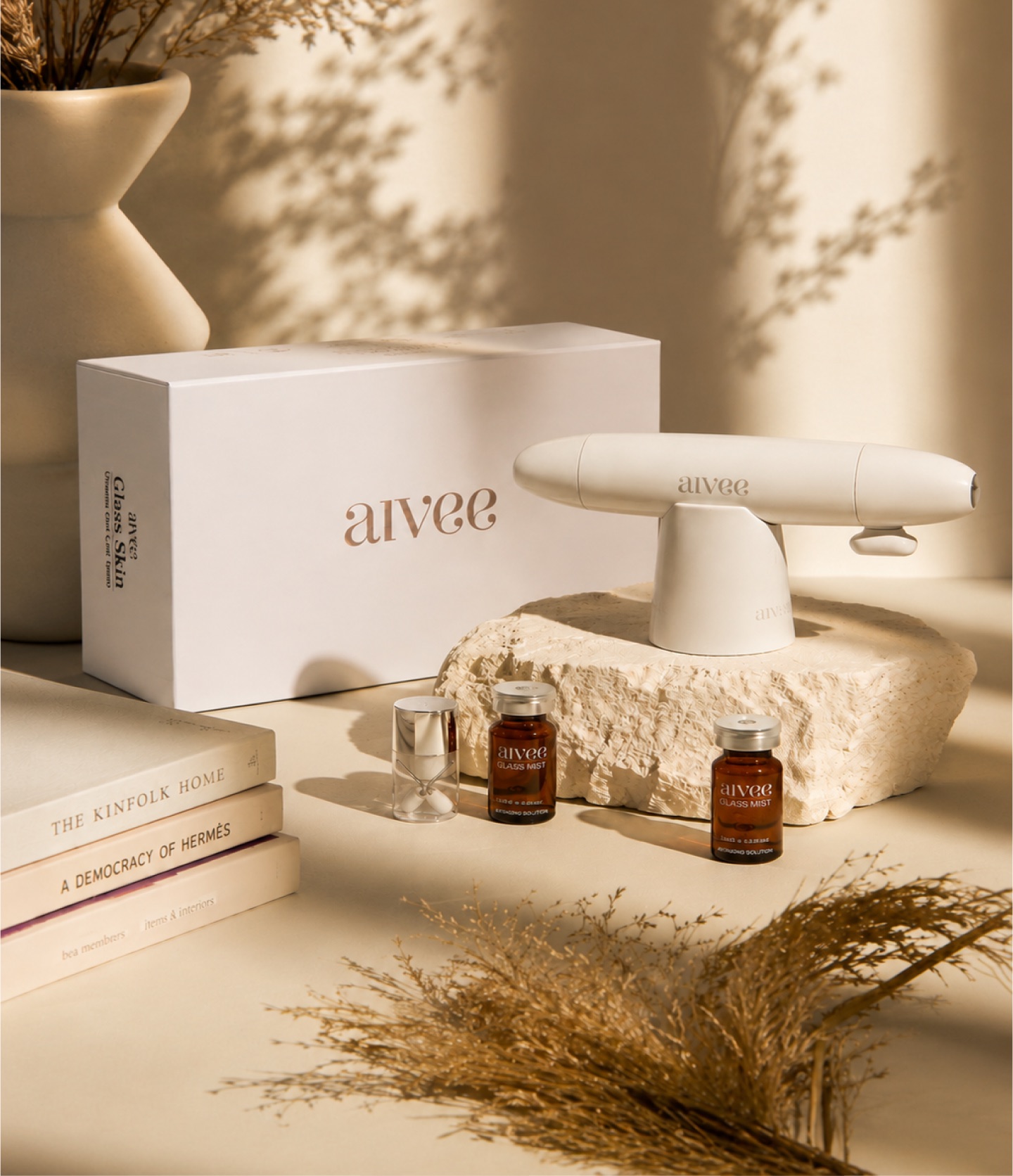 Aivee Glass anti-aging device and serum ampoules on a stone pedestal