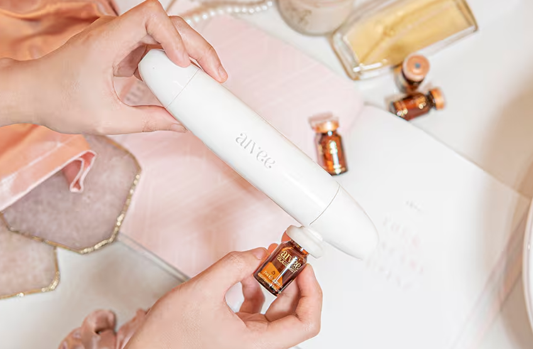 Hands drawing serum from an amber Aivee Glass ampoule into a white applicator