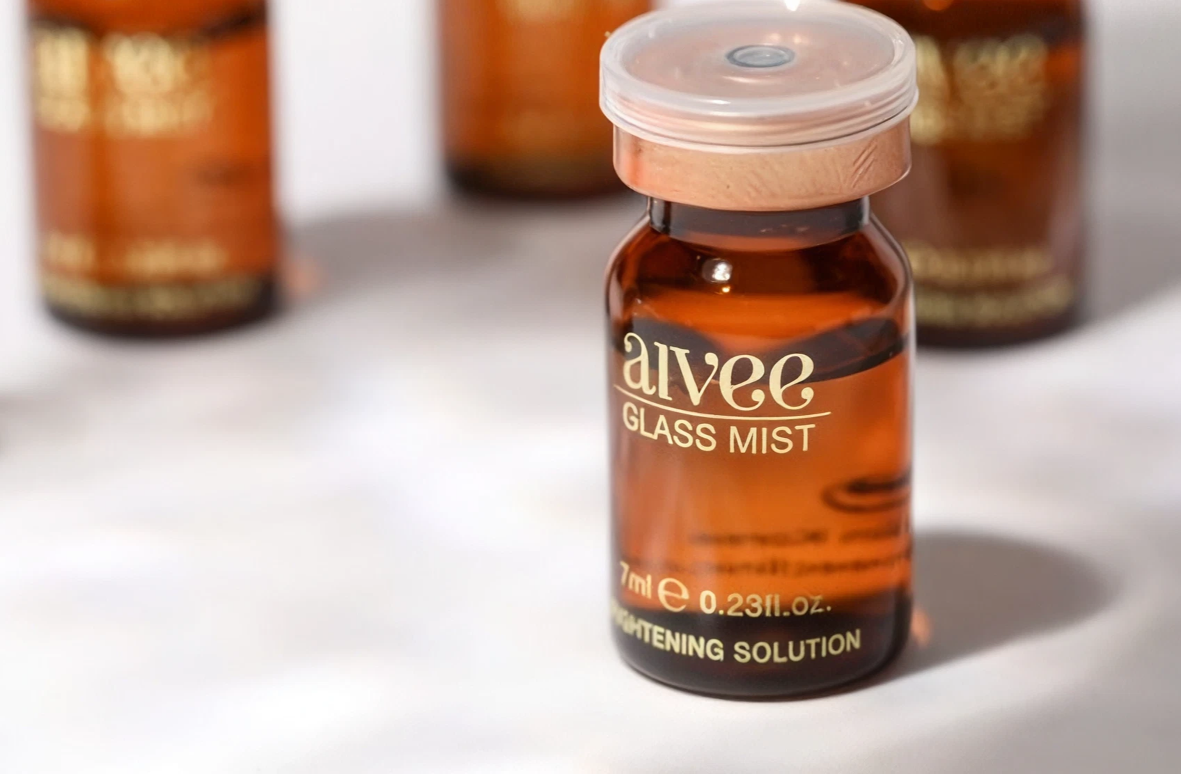 Aivee Glass Mist amber vial with a copper cap among out-of-focus ampoules