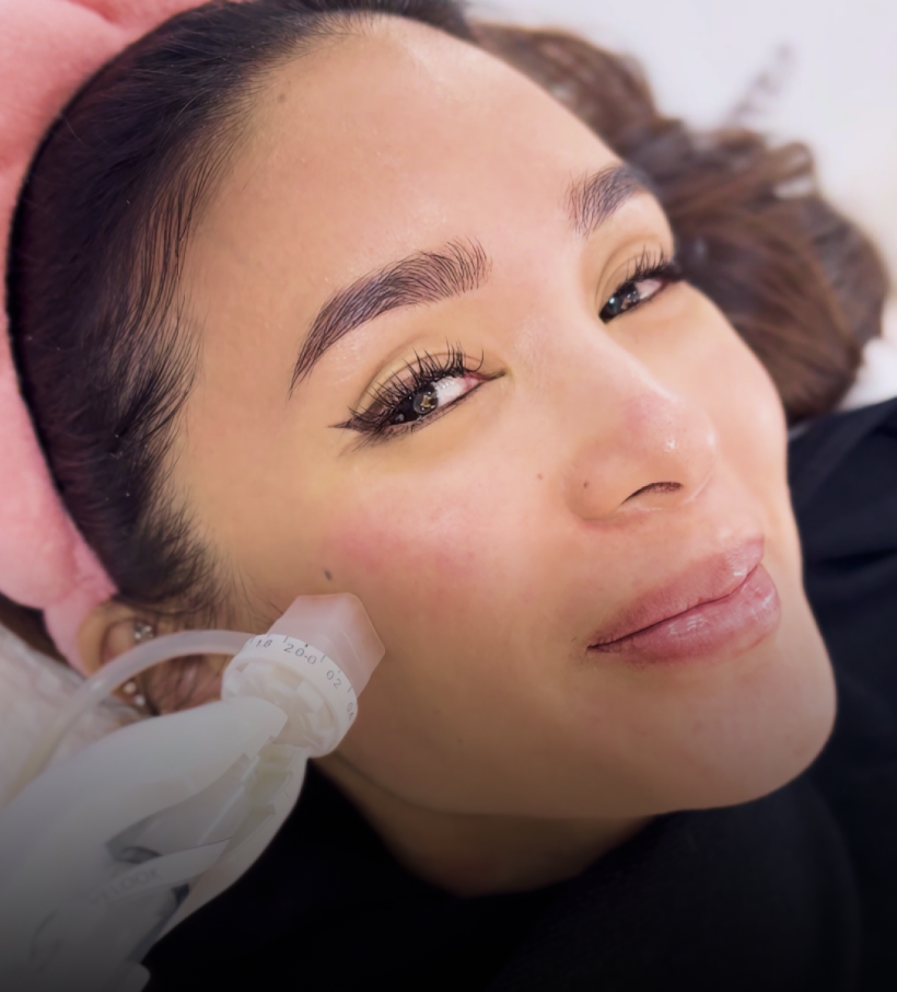 A client with a pink headband receiving an Aivee Dermashine facial treatment